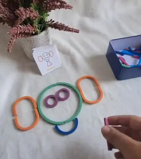 A face built from wooden sticks and rings, next to its shape card and the metal case.