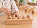 Child placing a knobbed cylinder into a wooden block